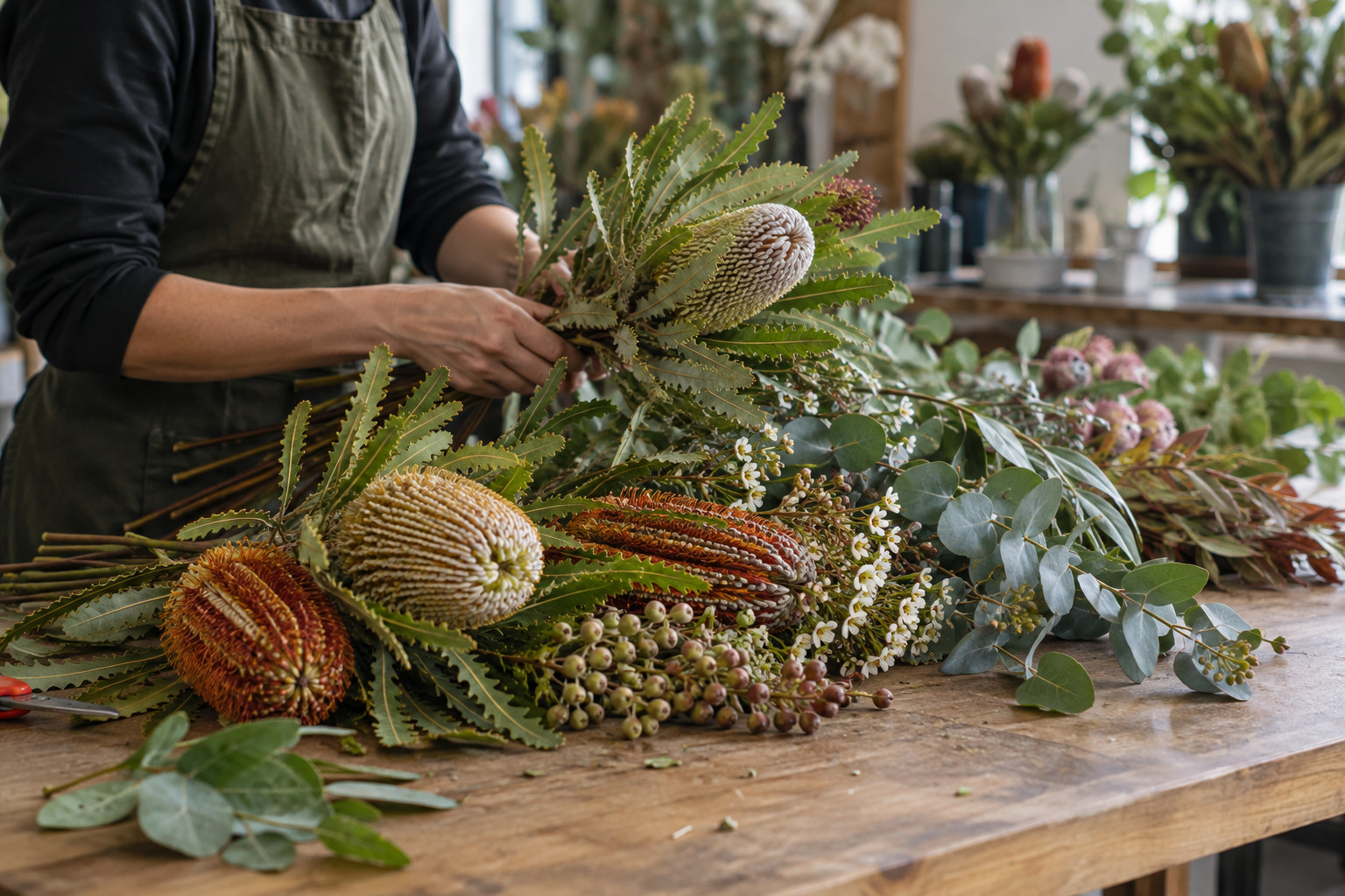 Florist preparing cut banksia stems and eucalyptus on a workbench